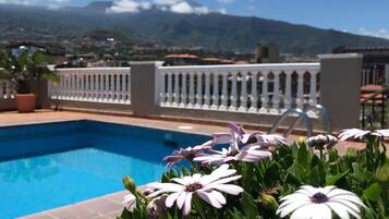 A swimming pool with a white railing and flowers in the foreground.