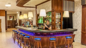 Un área de bar con una barra curva, taburetes de madera y lámparas colgantes.