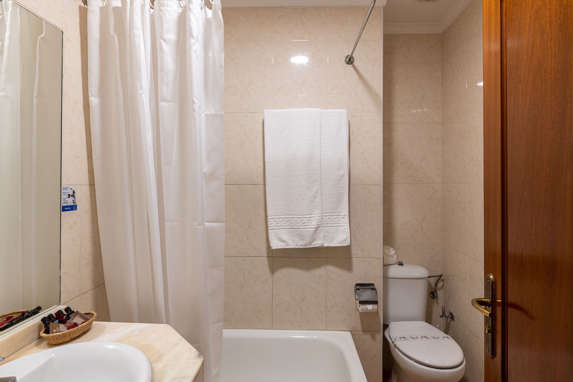 Un baño con bañera, inodoro y cortina de ducha.