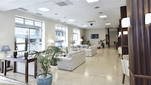 Un vestíbulo amplio con zona de estar, ventanas grandes y un televisor de pantalla plana montado en la pared.