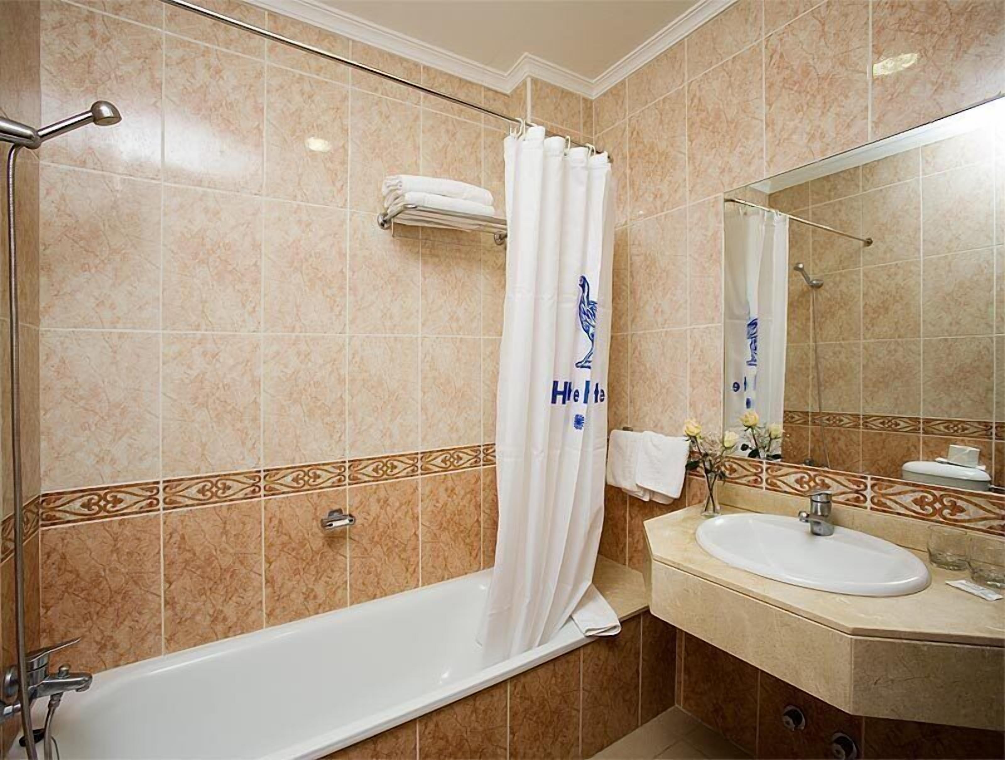 A bathroom with a bathtub, a sink, and a mirror.