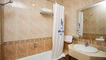 A bathroom with a bathtub, a sink, and a mirror.