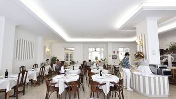 Un amplio comedor con varias mesas y sillas, una barra de buffet y un mostrador de recepción.