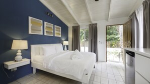A bedroom with a white bed, a nightstand with a lamp, a ceiling fan, and a view of the outdoors through a sliding door. - RipJack Inn (Cabo Velas)
