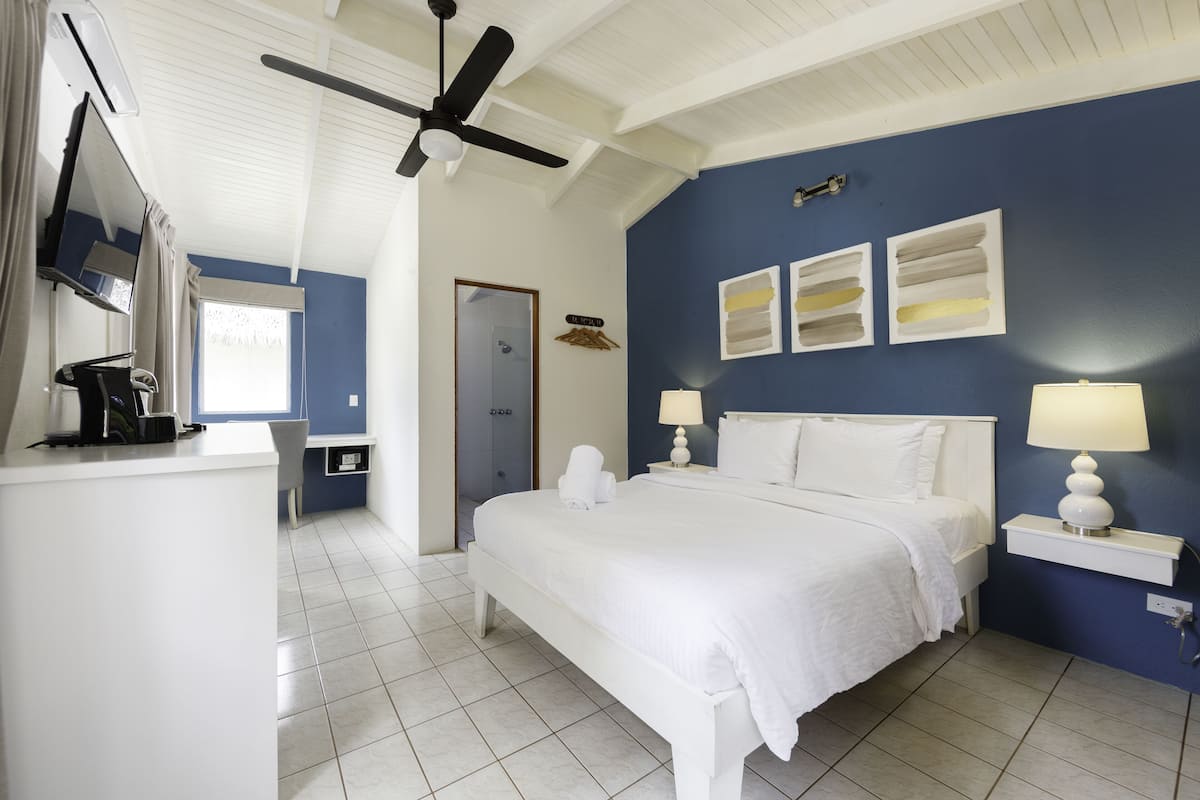 Un dormitorio con cama, mesitas de noche, ventilador de techo y obras de arte en la pared.