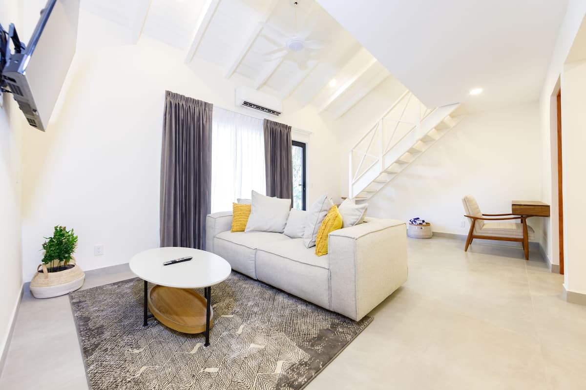 Una sala de estar moderna con un sofá, una mesa de centro y una escalera.