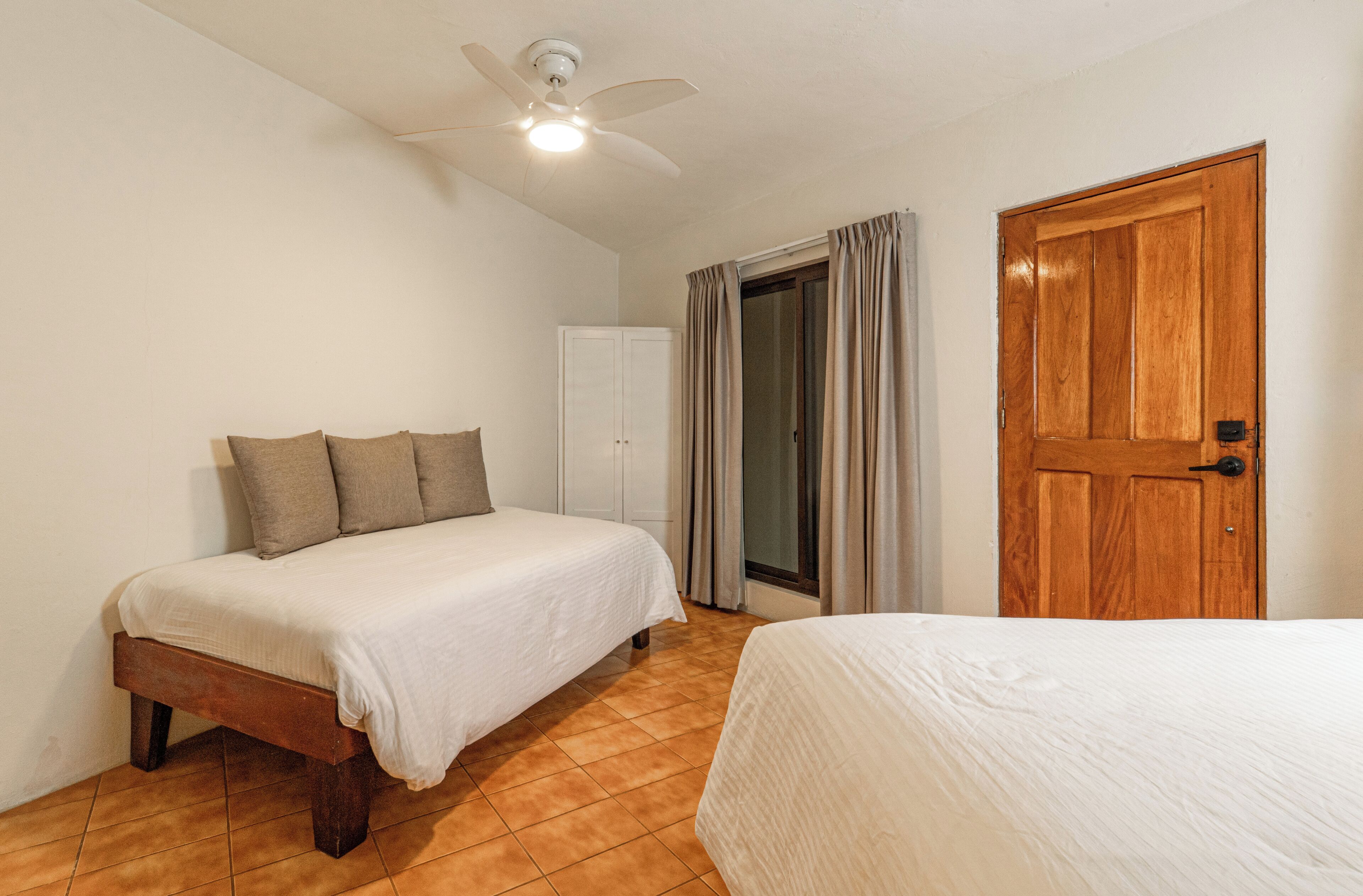 Ein Schlafzimmer mit Bett, Kleiderschrank, Tür und Deckenventilator.