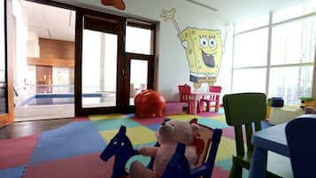 Children can play and relax in this spacious room with a play area featuring a colorful play mat, toys, and a fun wall mural.
