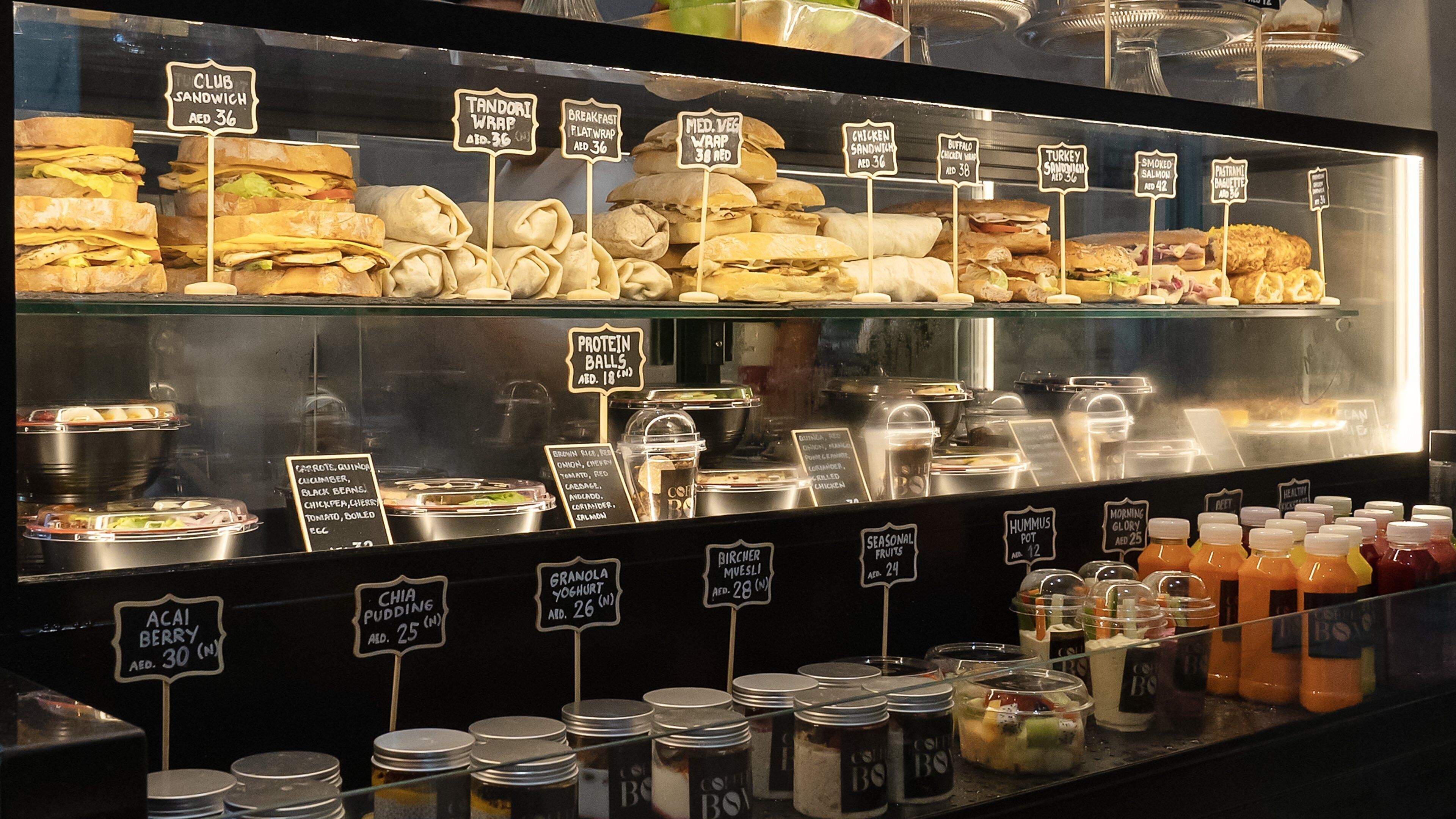 Een etalage met verschillende belegde broodjes, wraps en sauzen.