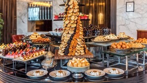 Ein Buffet mit verschiedenen Desserts und Gebäck, darunter eine große Kuchentürme, auf Tischen angerichtet.