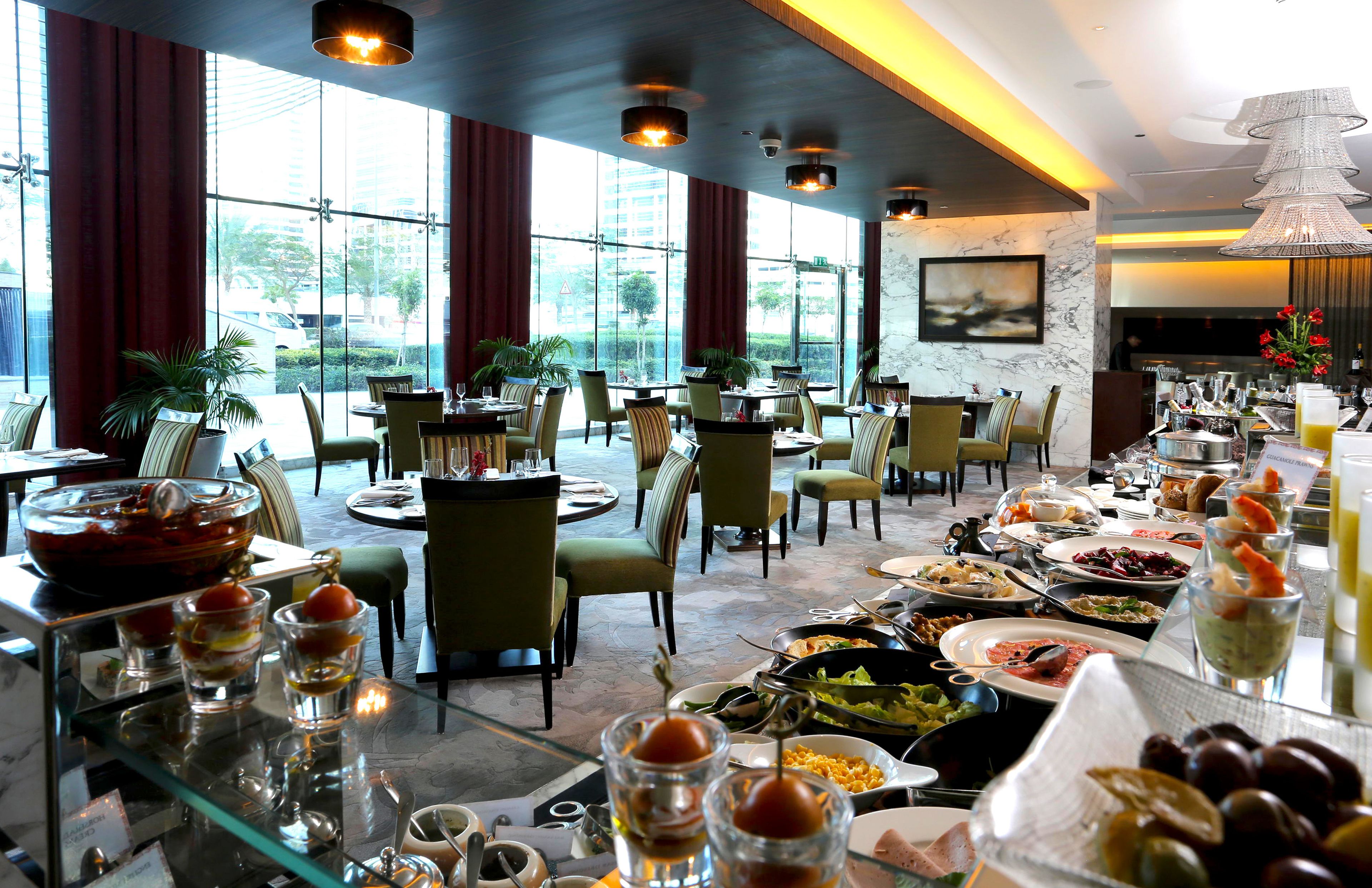 Restaurante com serviço de buffet, amplas janelas e design de interiores moderno.