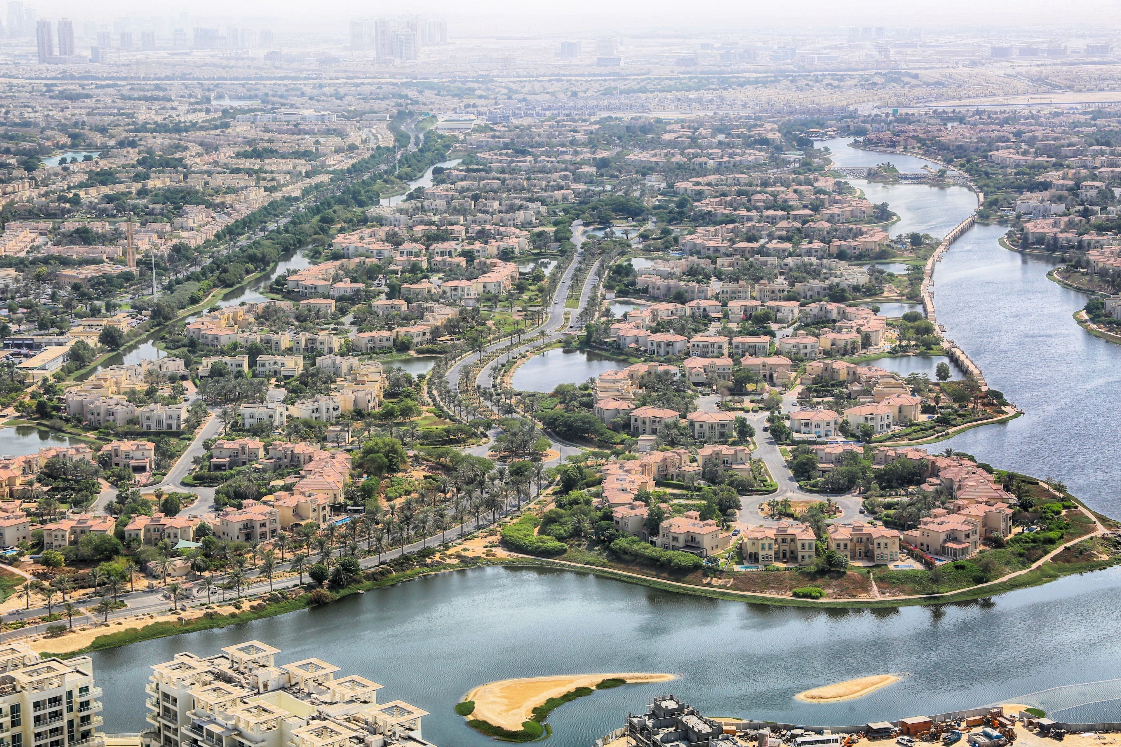 A residential area with a river running through it, surrounded by houses and greenery.