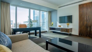 Ein modernes Wohnzimmer mit Sofa, Couchtisch, Fernseher und Blick auf die Stadt durch große Fenster.