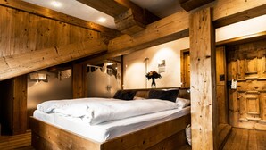 A wooden bed in a room with exposed beams and wooden walls. - Lifestyle & Spa Hotel Grächerhof (Graechen)