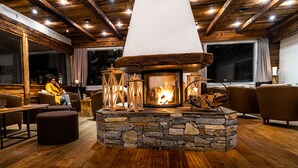 A cozy interior with a stone fireplace, wooden ceiling beams, and comfortable seating. - Lifestyle & Spa Hotel Grächerhof (Graechen)