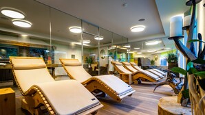 A spa area with multiple sun loungers, a wooden floor, and a large mirror reflecting the interior. - Lifestyle & Spa Hotel Grächerhof (Graechen)