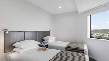 Habitación de hotel con dos camas, un ventanal y vistas a la ciudad, y un cabecero moderno.