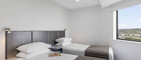 A hotel room with two beds, a large window with a city view, and a modern headboard.