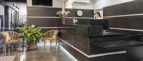 Una moderna recepción con un televisor de pantalla plana, un reloj y una planta en maceta.