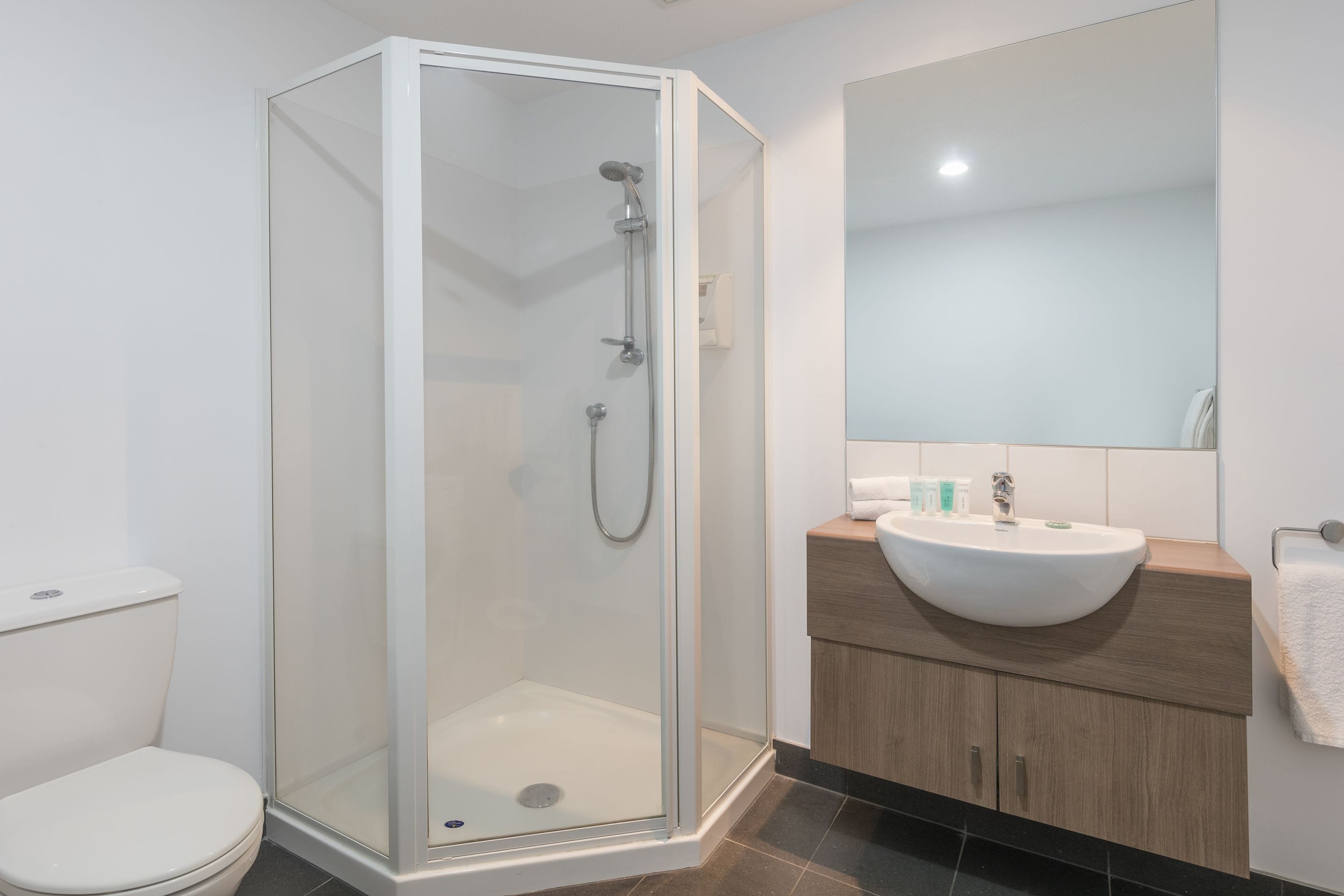 A modern bathroom with a glass-enclosed shower, a white sink, and a wooden vanity.