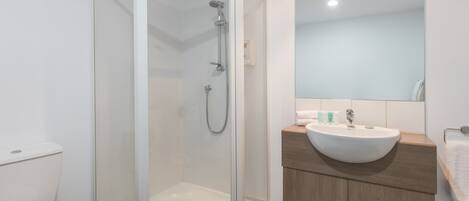 A modern bathroom with a glass-enclosed shower, a white sink, and a wooden vanity.
