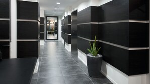 Un pasillo moderno con paneles de pared blanco y negro, una planta en maceta y una recepción al fondo.