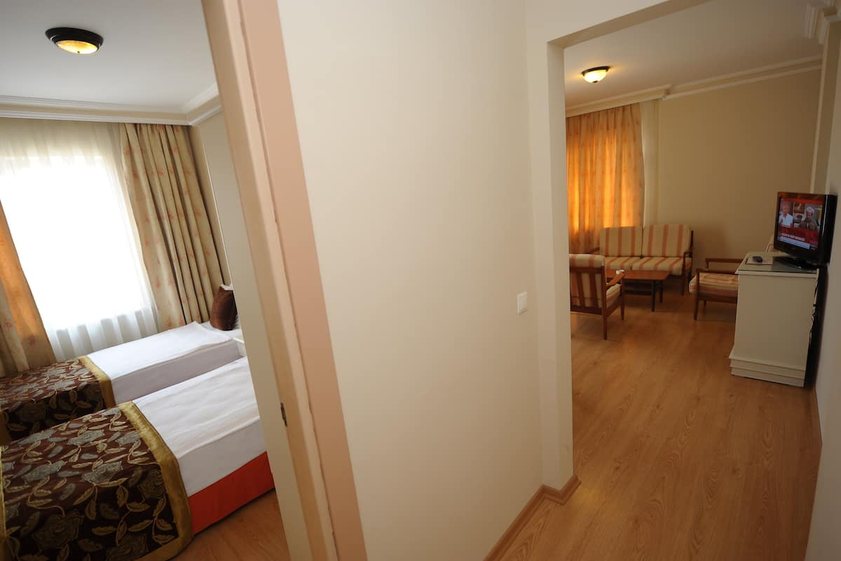Une chambre d’hôtel avec deux lits, un bureau, une chaise et un téléviseur.