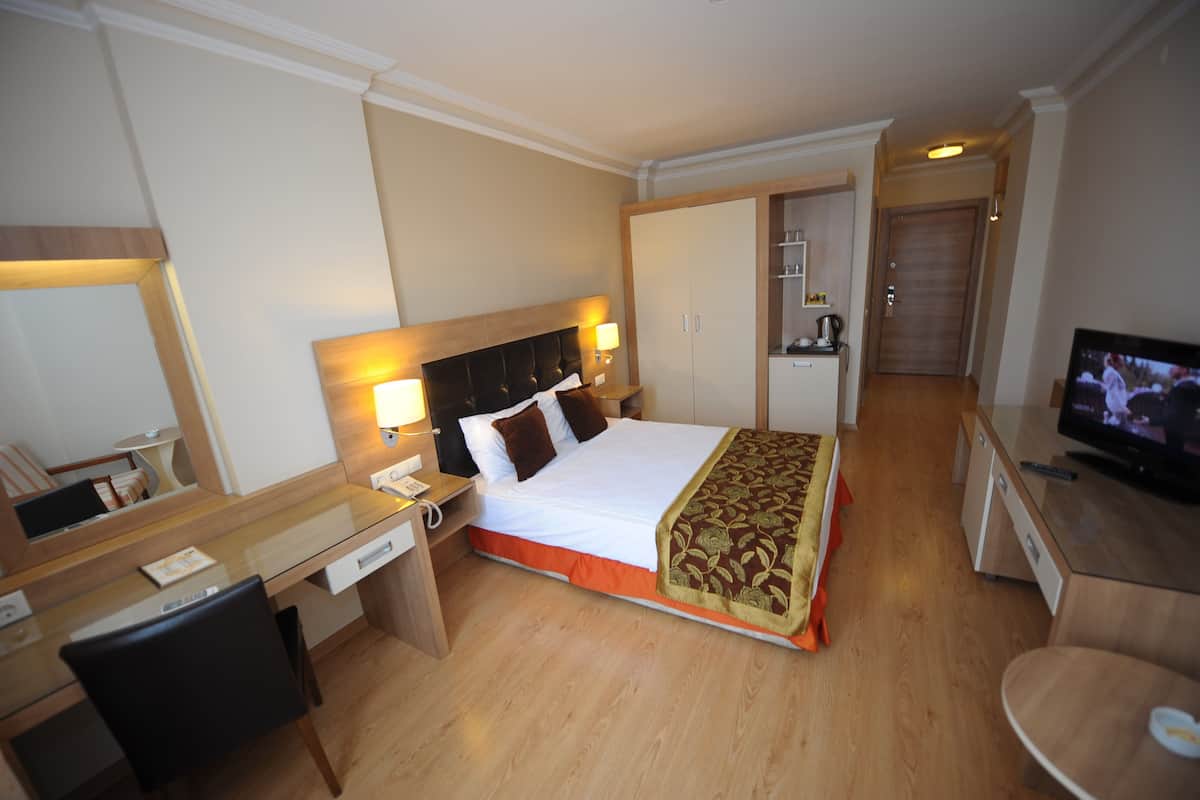 Une chambre d’hôtel équipée d’un lit, d’un bureau, d’une chaise, d’une télévision et d’une armoire.
