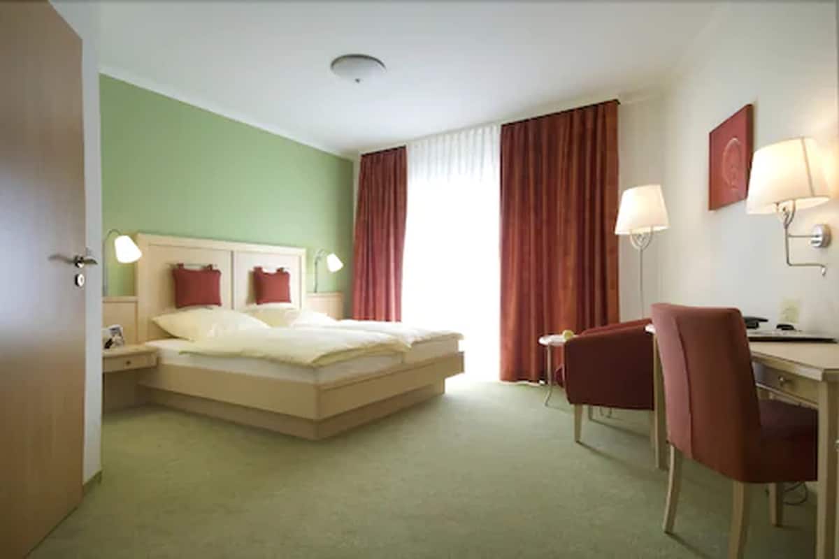 Ein Hotelzimmer mit Bett, Schreibtisch, Stuhl und zwei Lampen.