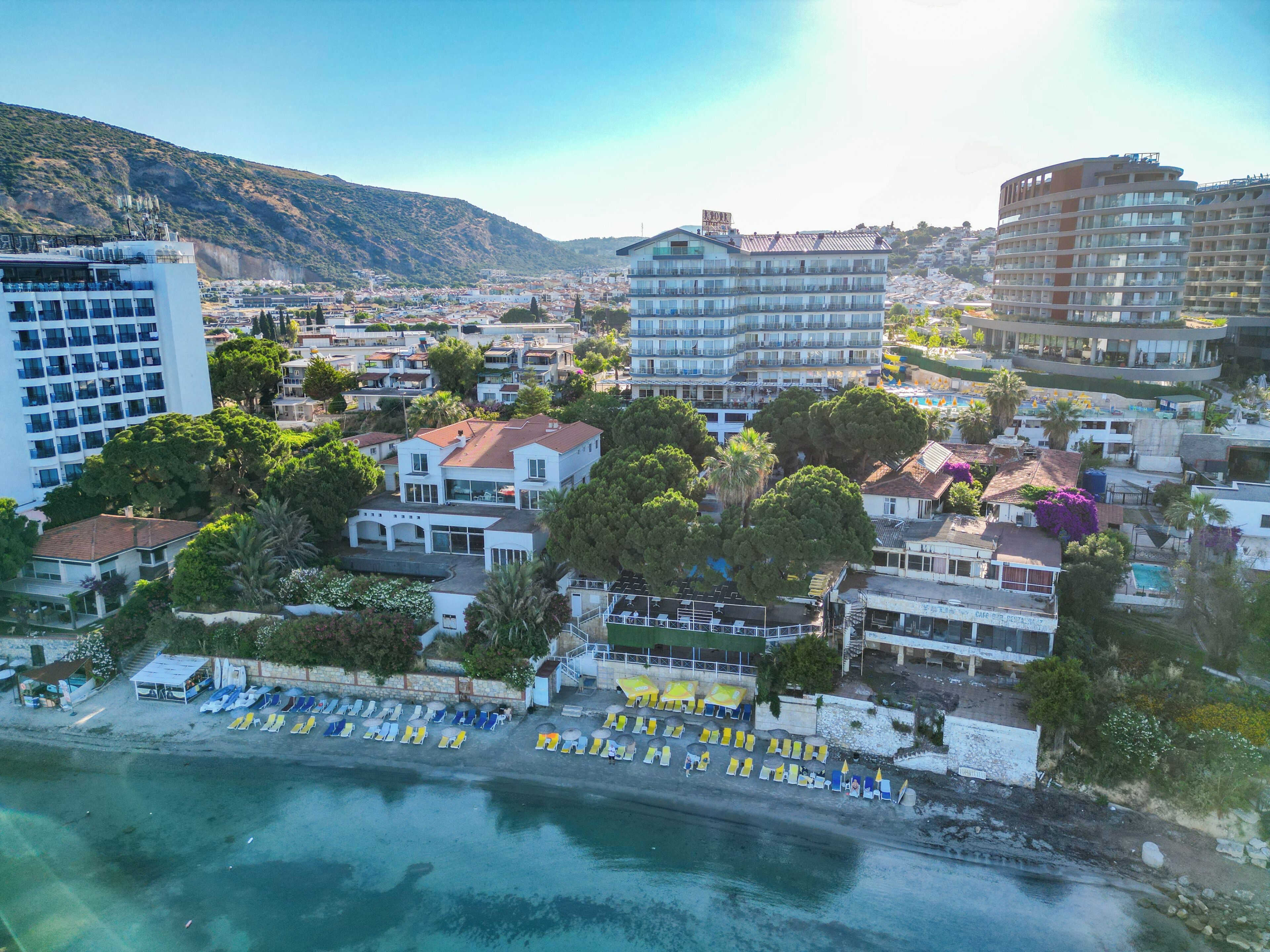 A coastal town with a beach, hotel buildings, and a mountainous backdrop.