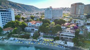 A coastal town with a beach, hotel buildings, and a mountainous backdrop.