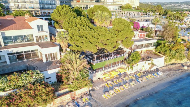An aerial view of a coastal hotel with a beach area, including sun loungers and umbrellas. - Arora Hotel (Kusadasi)