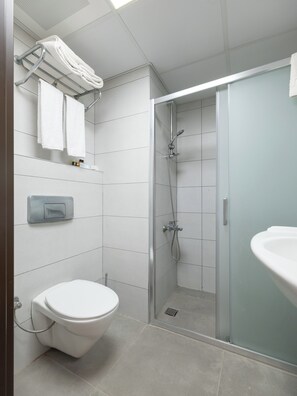 A modern bathroom with a toilet, a glass-enclosed shower, and a sink. - Arora Hotel (Kusadasi)