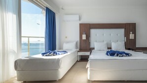 A hotel room with two beds, a window with curtains, a wooden headboard, and an air conditioning unit. - Arora Hotel (Kusadasi)
