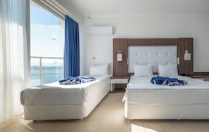 Ein Hotelzimmer mit zwei Betten, einem Vorhangfenster, einem Holz-Kopfteil und einer Klimaanlage.