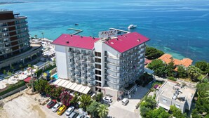 A multi-story hotel with balconies, a red roof, and a view of the sea. - Arora Hotel (Kusadasi)