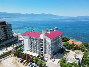 A multi-story hotel with balconies, a red roof, and a view of the sea. - Arora Hotel (Kusadasi)