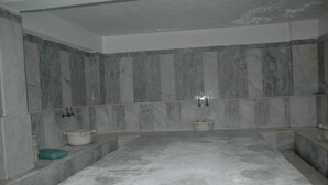A bathroom with marble walls, a bathtub, and a sink. - Arora Hotel (Kusadasi)