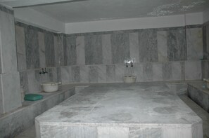 A bathroom with marble walls, a bathtub, and a sink. - Arora Hotel (Kusadasi)