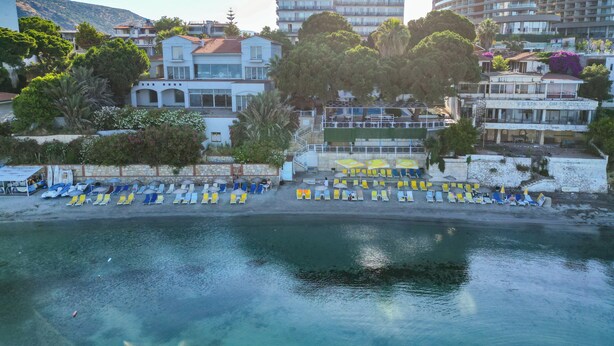 A coastal hotel with multiple floors, a beachside location, and a variety of seating arrangements. - Arora Hotel (Kusadasi)