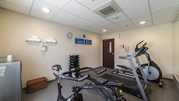 A gym with stationary bikes, a treadmill, and a weight rack.