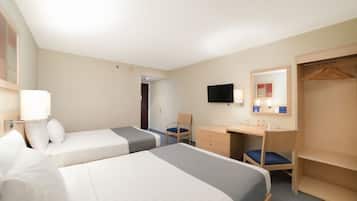 Une chambre d’hôtel avec deux lits, un bureau, une chaise, une armoire et un téléviseur.
