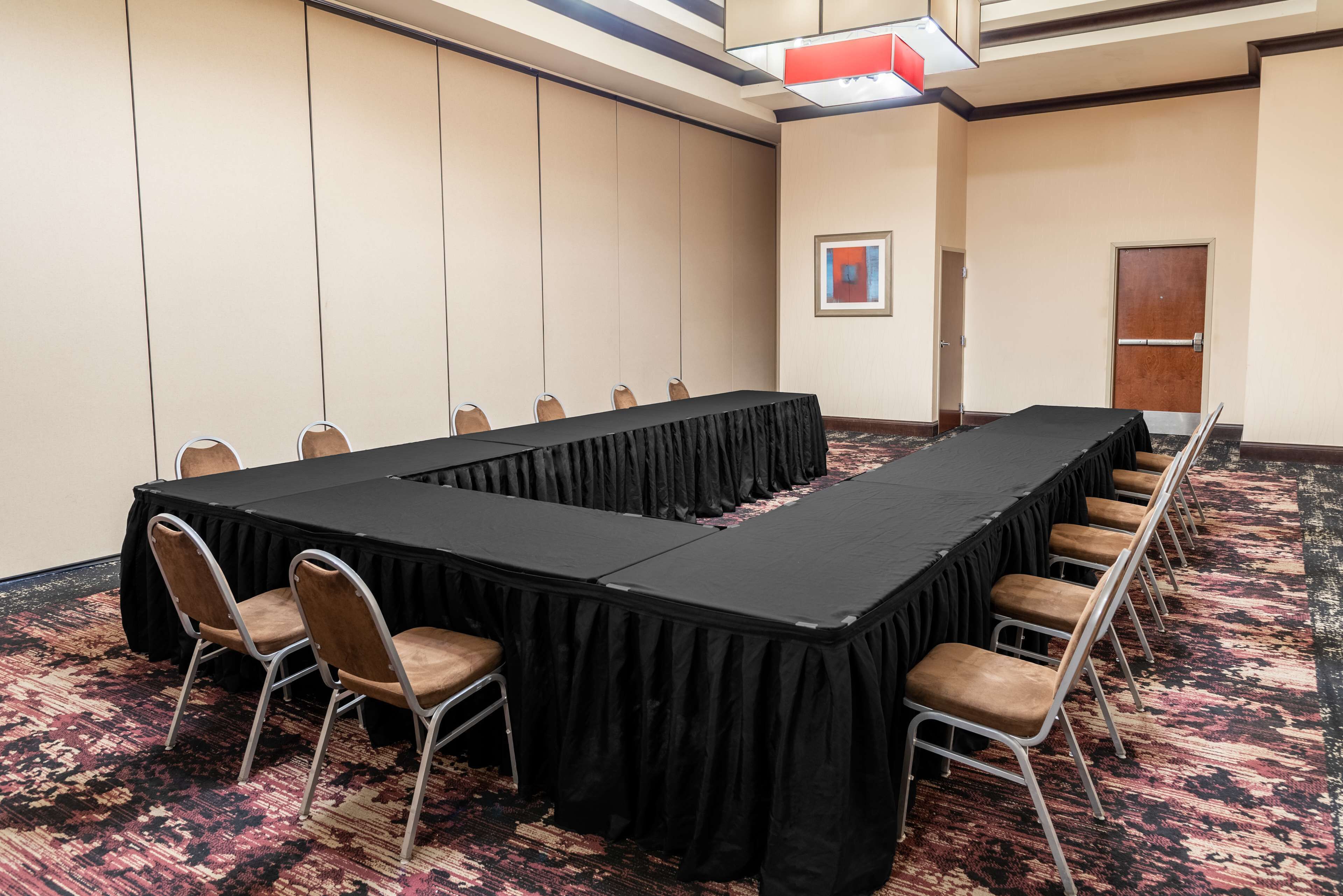 A conference room with a long table, chairs, and a carpeted floor.