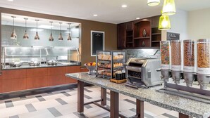 A breakfast bar with a variety of food items, including fruits, pastries, and cereal. - Hilton Garden Inn North Little Rock (North Little Rock)