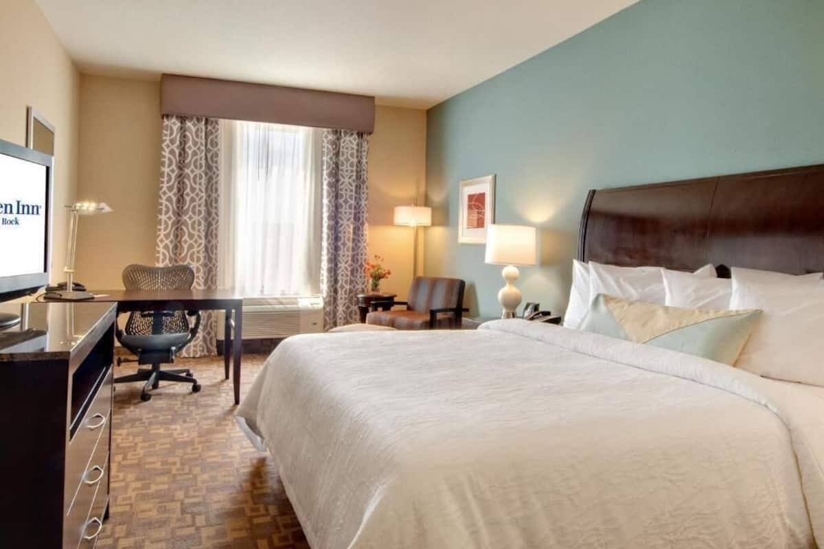 A hotel room with a large bed, a desk with a computer, a chair, and a TV.