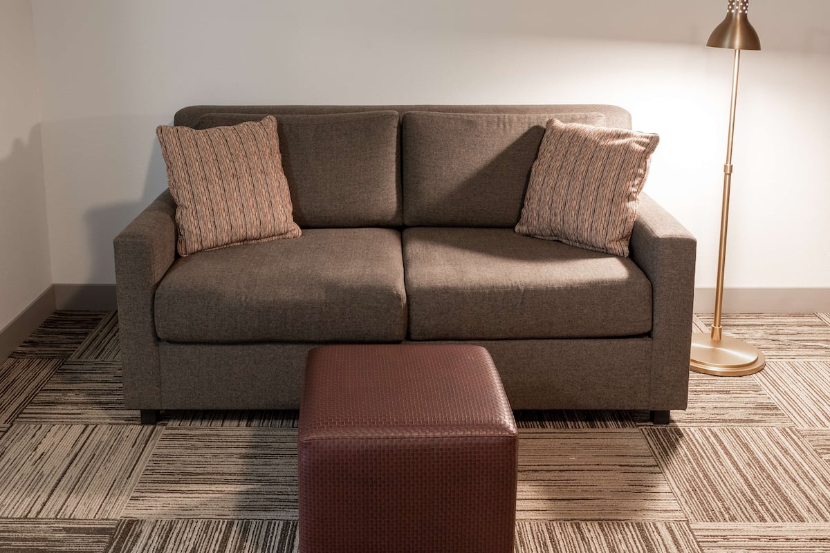 A modern living room with a sofa and ottoman, a floor lamp, and a patterned carpet.
