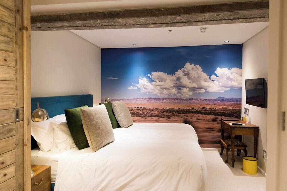 A bedroom with a large bed, a desk, and a TV.
