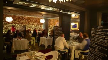 En restaurang med dukade bord, en meny skriven på en tavla och en kristallkrona.