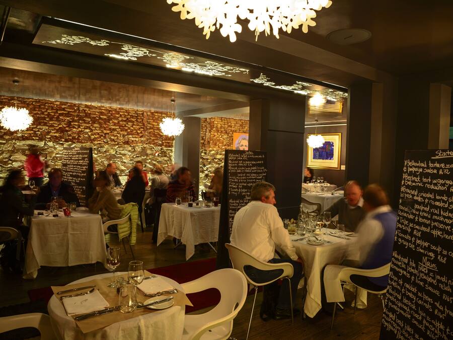 En restaurang med dukade bord, en meny skriven på en tavla och en kristallkrona.