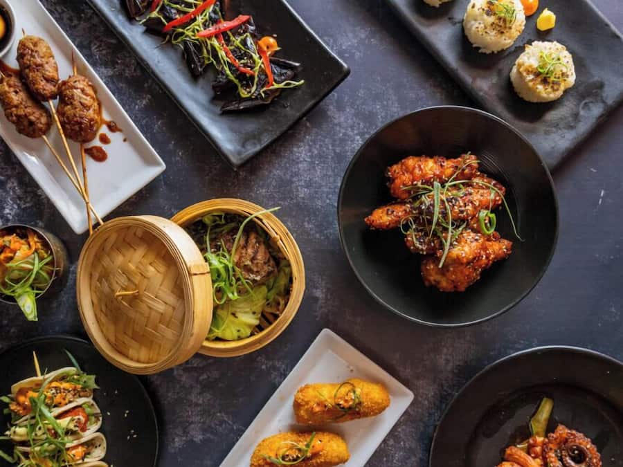 Variedad de platillos, incluyendo brochetas, frituras y un tazón de ensalada.